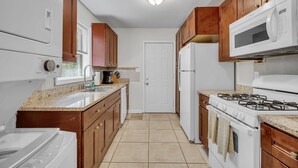 Una cucina funzionale con mobili in legno, forno a microonde, piano cottura e lavastoviglie.