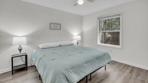 Una camera da letto con un letto, due lampade da comodino, una ventola a soffitto, una finestra e un interruttore a parete.