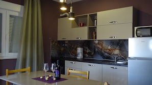 A modern kitchen with a marble backsplash, a built-in microwave, and a stainless steel refrigerator. - Apartmani Luna (Sukosan)