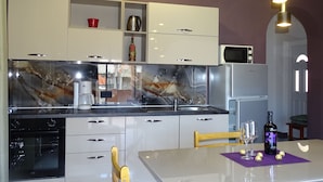 A modern kitchen with a marble backsplash, stainless steel appliances, and a dining area with a table set for two. - Apartmani Luna (Sukosan)