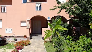 A building with a central entrance, a number '2' above the door, and a small balcony with a railing. - Apartmani Luna (Sukosan)