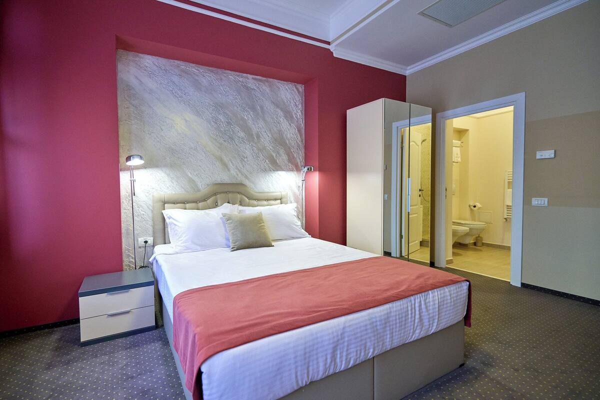 Une chambre d’hôtel avec un lit, une table de chevet et un grand miroir.