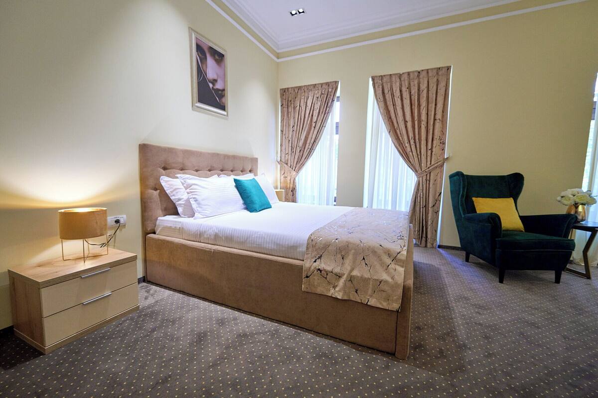 Une chambre d’hôtel avec un grand lit, une table de chevet, une chaise et des rideaux.