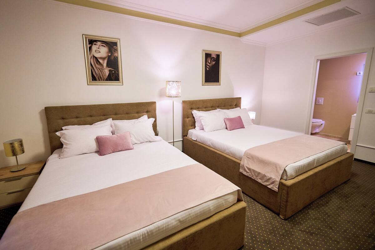 Une chambre d’hôtel avec deux lits, une table de chevet avec une lampe et une porte donnant sur une salle de bain.