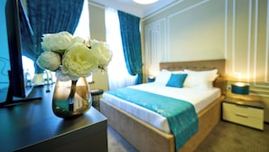 Een hotelkamer met een bed, nachtkastje en een bloemenvaas op een bureau.