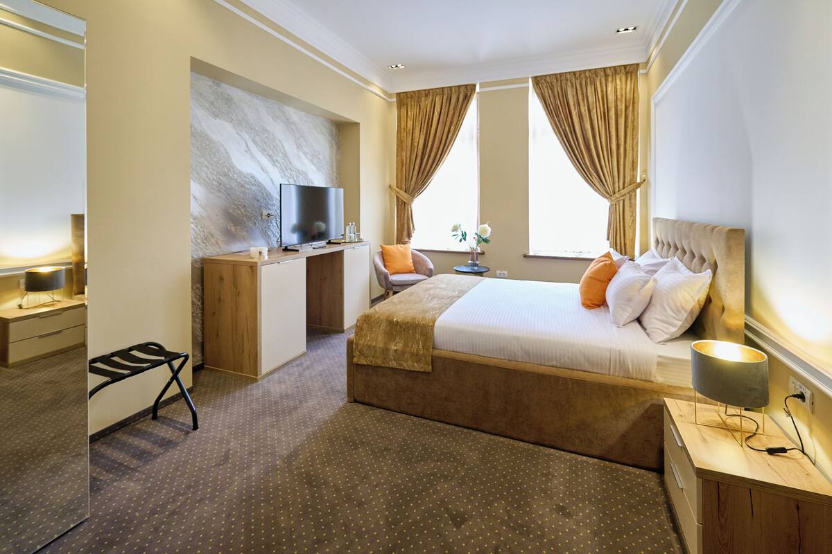 Une chambre d’hôtel avec un lit, un bureau, une télévision et une fenêtre avec des rideaux.