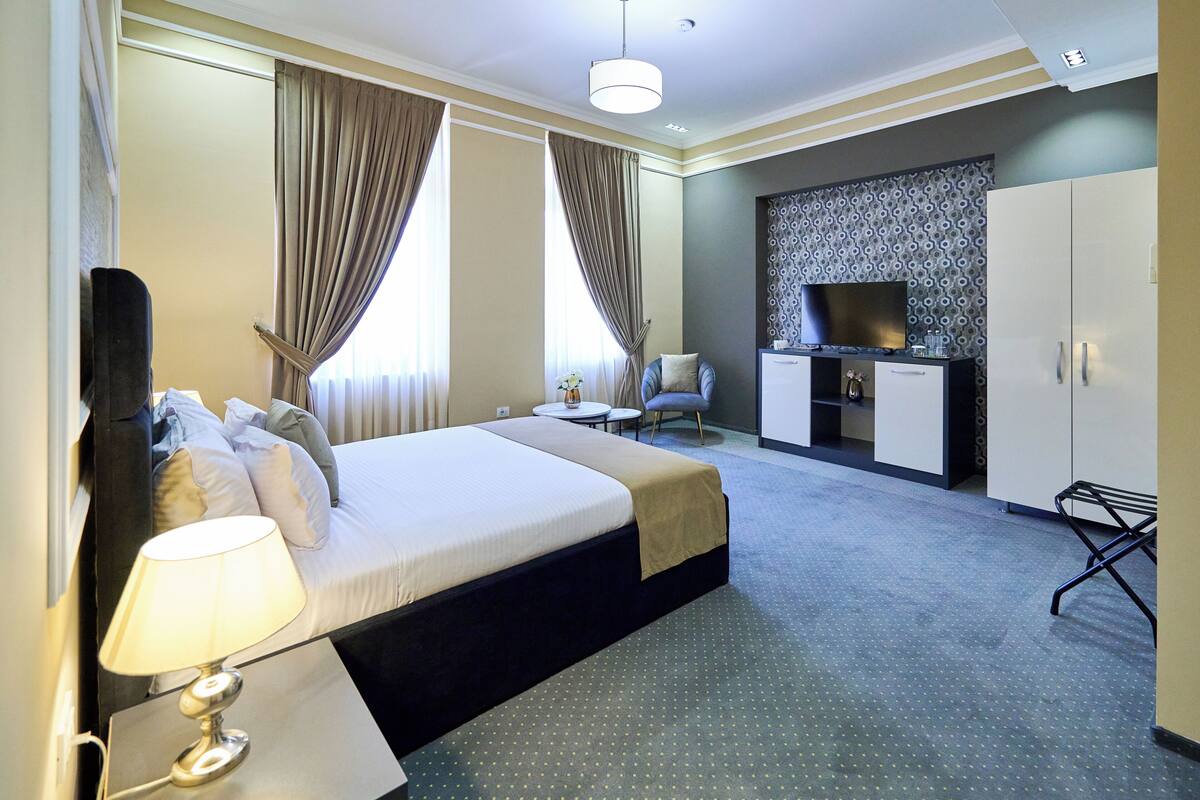 Une chambre d’hôtel équipée d’un lit, d’un bureau, d’une chaise, d’une télévision et d’une armoire.
