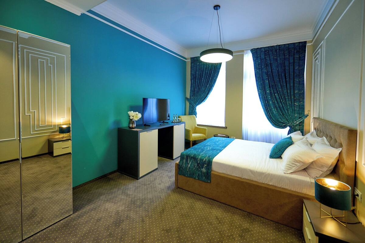 Une chambre d’hôtel avec un lit, un bureau, une chaise et un téléviseur.