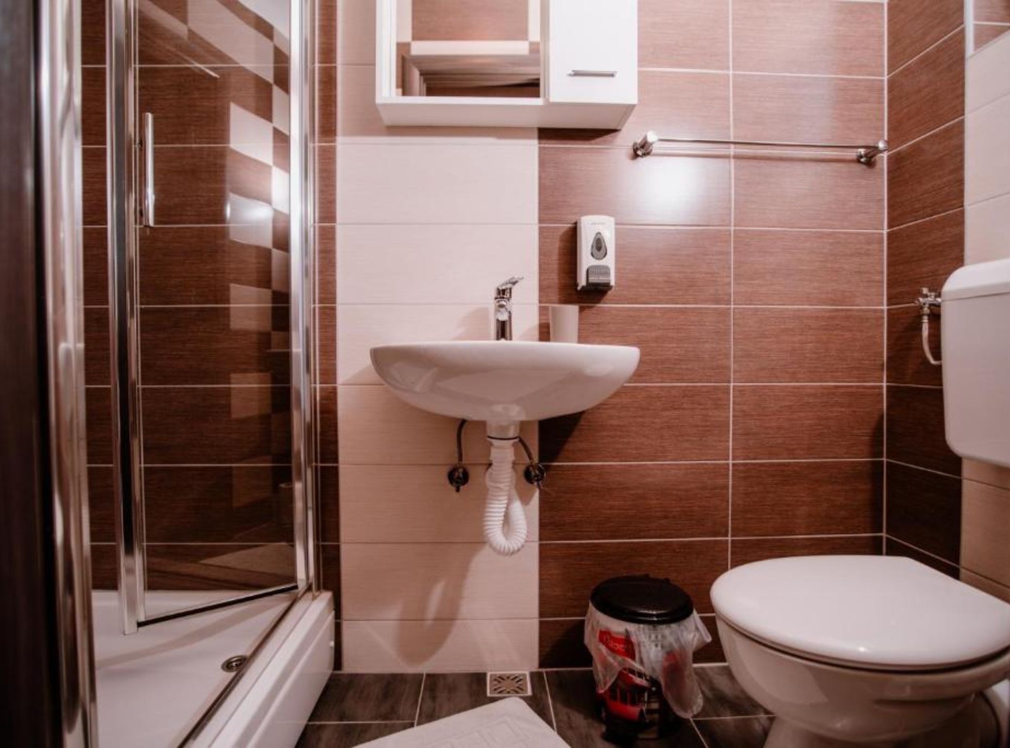A bathroom with a glass shower enclosure, a white sink, a toilet, and a towel rack.