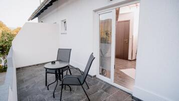 A patio with a table and chairs, a sliding glass door, and a tiled floor.