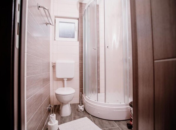 A bathroom with a toilet, a shower enclosure, and a small window. - Mountain Serenity Rooms (Plitvicka Jezera)