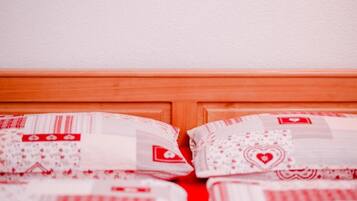 Una cama con cabecera de madera y almohadas con diseños rojo y blanco.