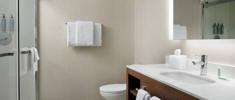 Ein modernes Badezimmer mit Duschkabine aus Glas, Toilette in Weiß, Holzwaschtisch mit Spüle und Spiegel.