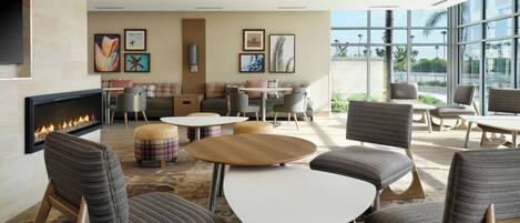 A modern lounge area with a fireplace, comfortable seating, and large windows offering a view.