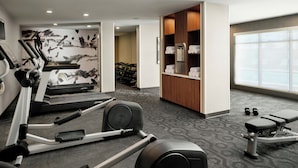 Un gimnasio con cintas de correr, elípticas y bancos de pesas.