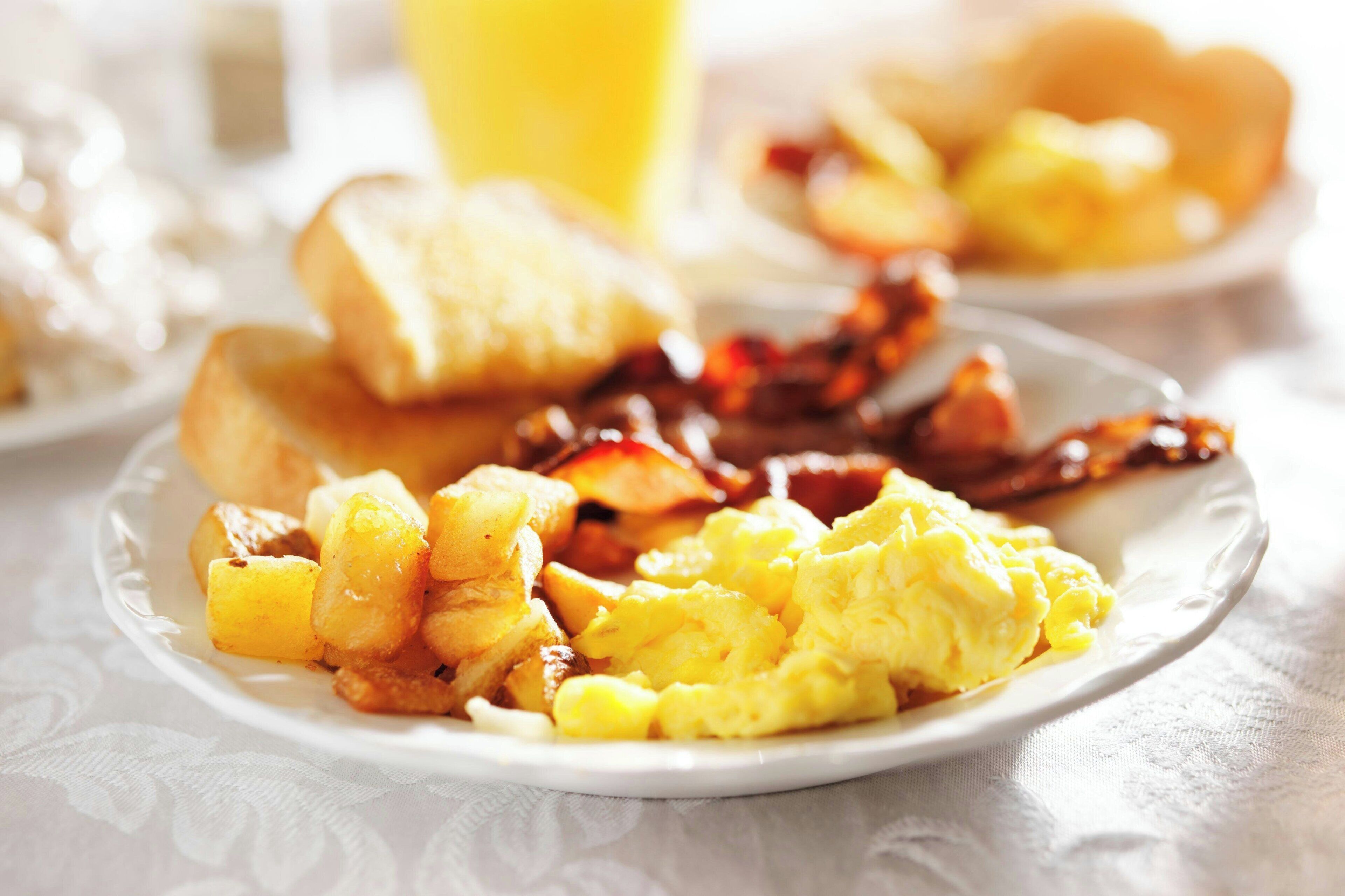 A breakfast plate with scrambled eggs, toast, and bacon.
