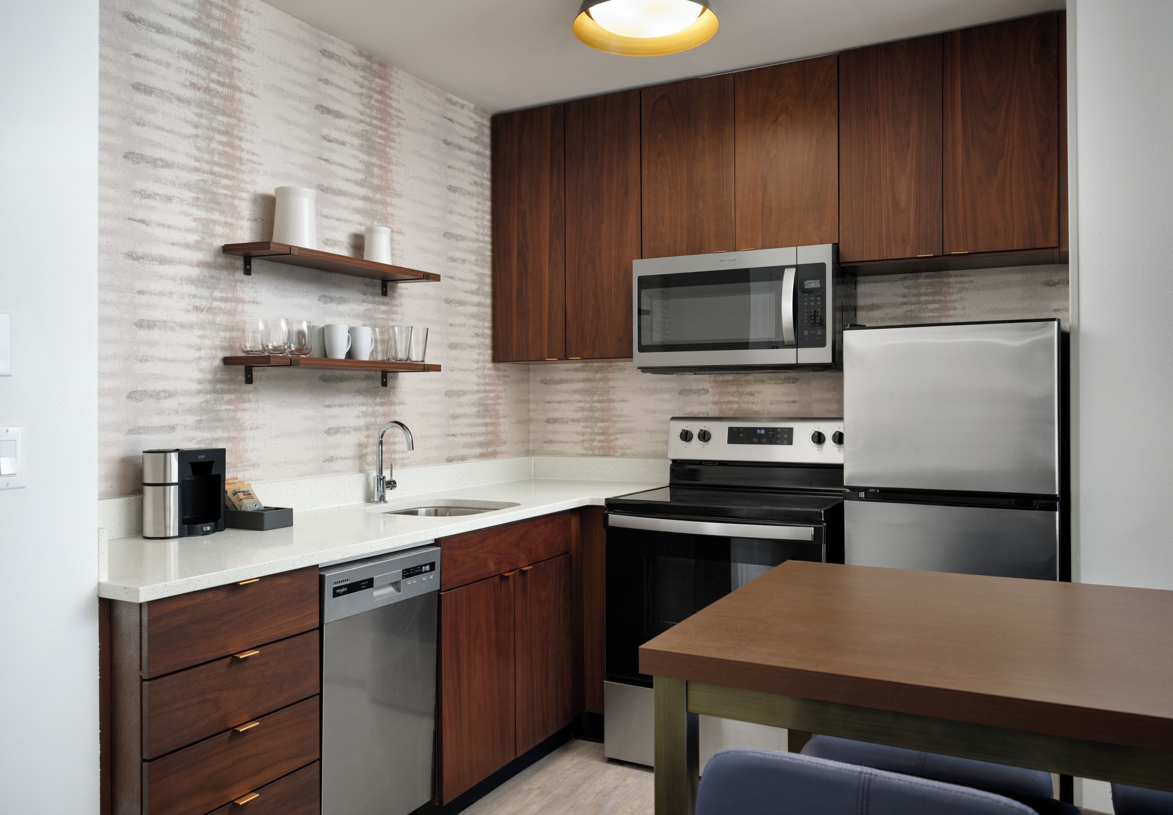 A modern kitchen with wooden cabinets, stainless steel appliances, and a white countertop.