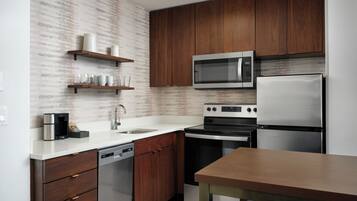 A modern kitchen with wooden cabinets, stainless steel appliances, and a white countertop.