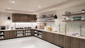 Una cocina moderna con armarios de madera, encimeras blancas y una variedad de electrodomésticos.