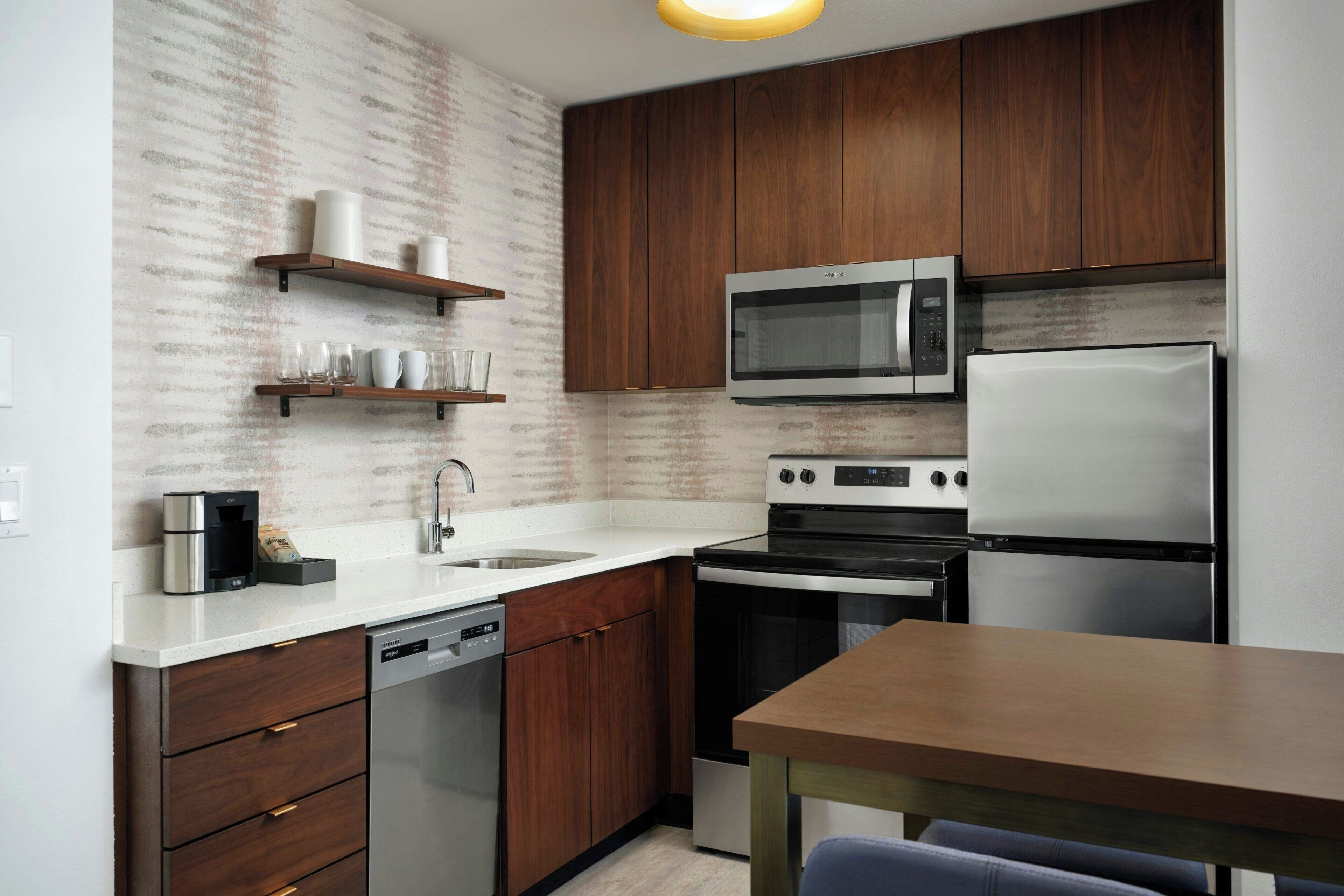 A modern kitchen with wooden cabinets, stainless steel appliances, and a built-in microwave.