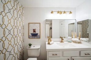 A modern bathroom with a white vanity, gold fixtures, and a large mirror. - The Gallery in Downtown Stamford (Stamford)