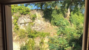 Un balcon avec une table et des chaises, donnant sur une colline rocheuse parsemée de verdure.