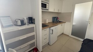 A compact kitchenette with a microwave, toaster, coffee maker, and a small refrigerator. There is a sink with a faucet and a countertop. - Balcony Studio Vacation Home (Unknown)