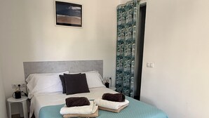 A neatly made bed with a blue quilt, two pillows, and two folded towels. - Balcony Studio Vacation Home (Unknown)