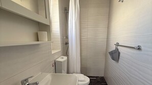 A bathroom with a white sink, toilet, and shower curtain. - Balcony Studio Vacation Home (Unknown)