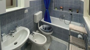 A modern bathroom with a bathtub, two sinks, a toilet, and a shower. - Pearl Diva Apartment (Palermo)