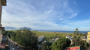 A view from a balcony overlooking a coastal area with buildings, trees, and a clear sky. - Pearl Diva Apartment (Palermo)