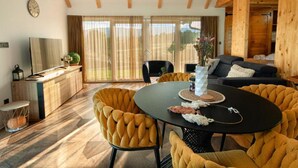 A modern living room with a round black table, yellow upholstered chairs, a black sofa, and a wooden ceiling. - Family Resort Plitvice Lakes (Plitvicka Jezera)