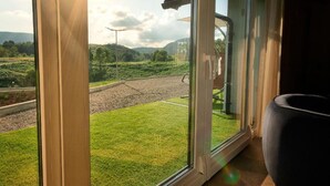 A room with a large window offering a view of a grassy area and a road. - Family Resort Plitvice Lakes (Plitvicka Jezera)