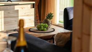 A cozy living room with a wooden coffee table holding a fruit bowl, a TV, and a bottle of wine. - Family Resort Plitvice Lakes (Plitvicka Jezera)