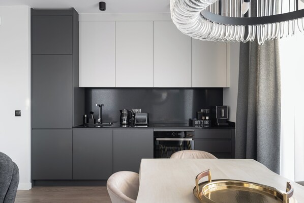 Une cuisine moderne avec des meubles gris, une machine à café et une table à manger agrémentée d’un plateau.