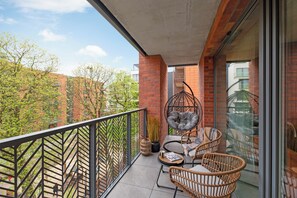 A balcony with wicker chairs, a hanging chair, and a potted plant. - Lion Apartments - SCALA City Center (Gdansk)