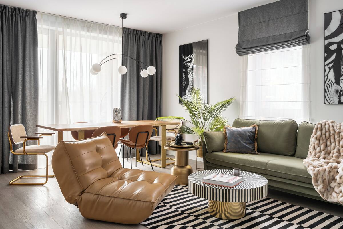 Ein modernes Wohnzimmer mit Ledersessel, rundem Couchtisch und einem grünen Sofa.