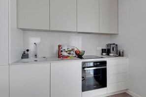 A modern kitchen with white cabinetry, a built-in dishwasher, and an oven.
