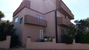 A two-story building with a flat roof, a central entrance, and a small porch with potted plants. - Pansion Stones Murter (Murter-Kornati)