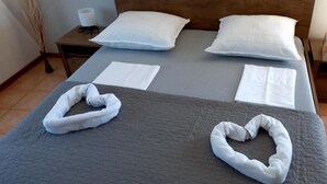 A neatly made bed with a grey quilt, two white pillows, and two white towels folded on the bed. - Pansion Stones Murter (Murter-Kornati)