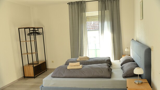 A neatly arranged bedroom with a bed, bedside tables, and a wardrobe. - Vacation apartment Taubersonne (Igersheim)
