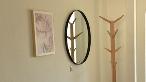 A hallway with a grey bench, a round mirror, and a wooden coat rack. - Vacation apartment Taubersonne (Igersheim)