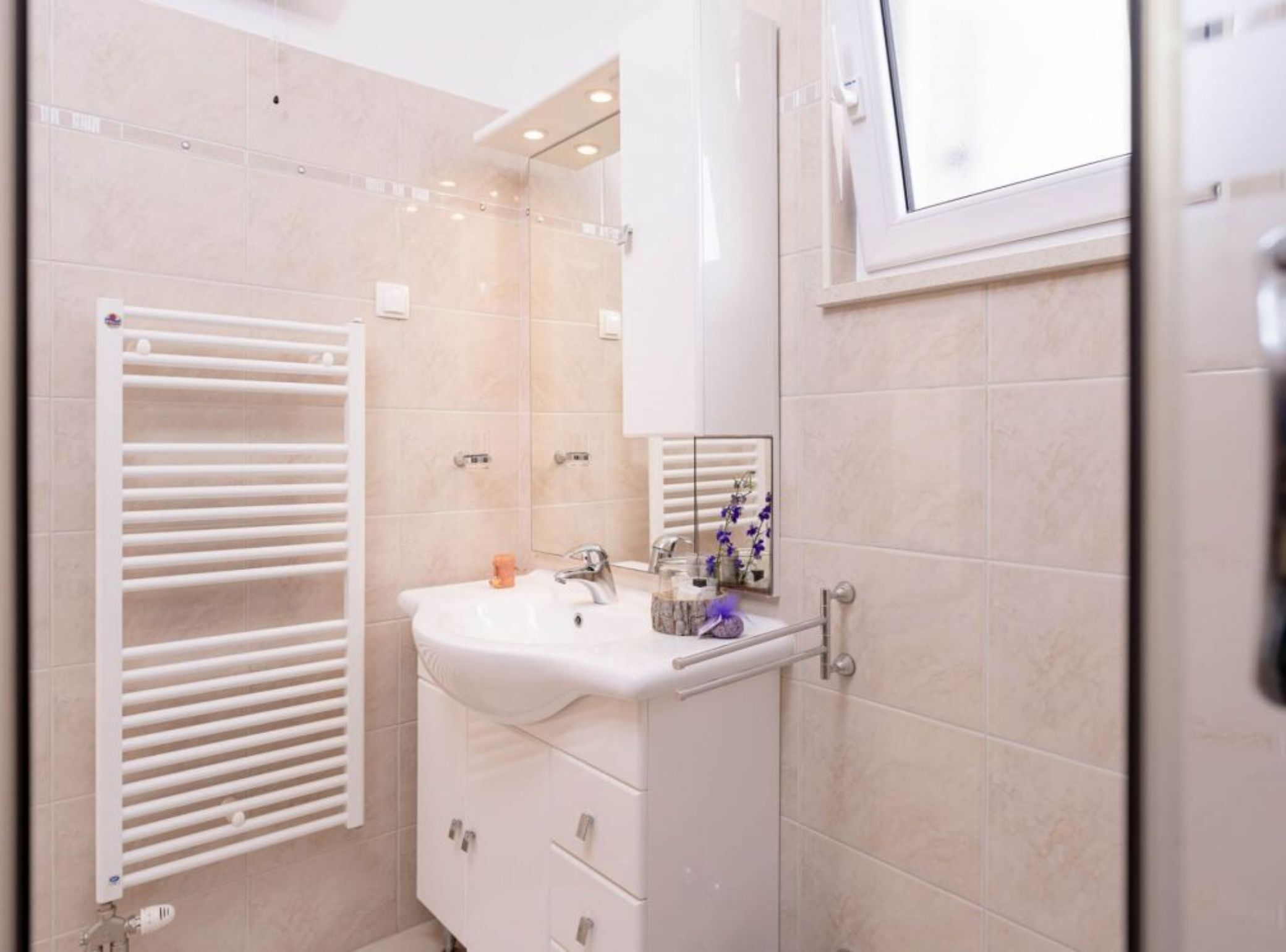 A modern bathroom with a white sink, a mirror, and a towel rack.