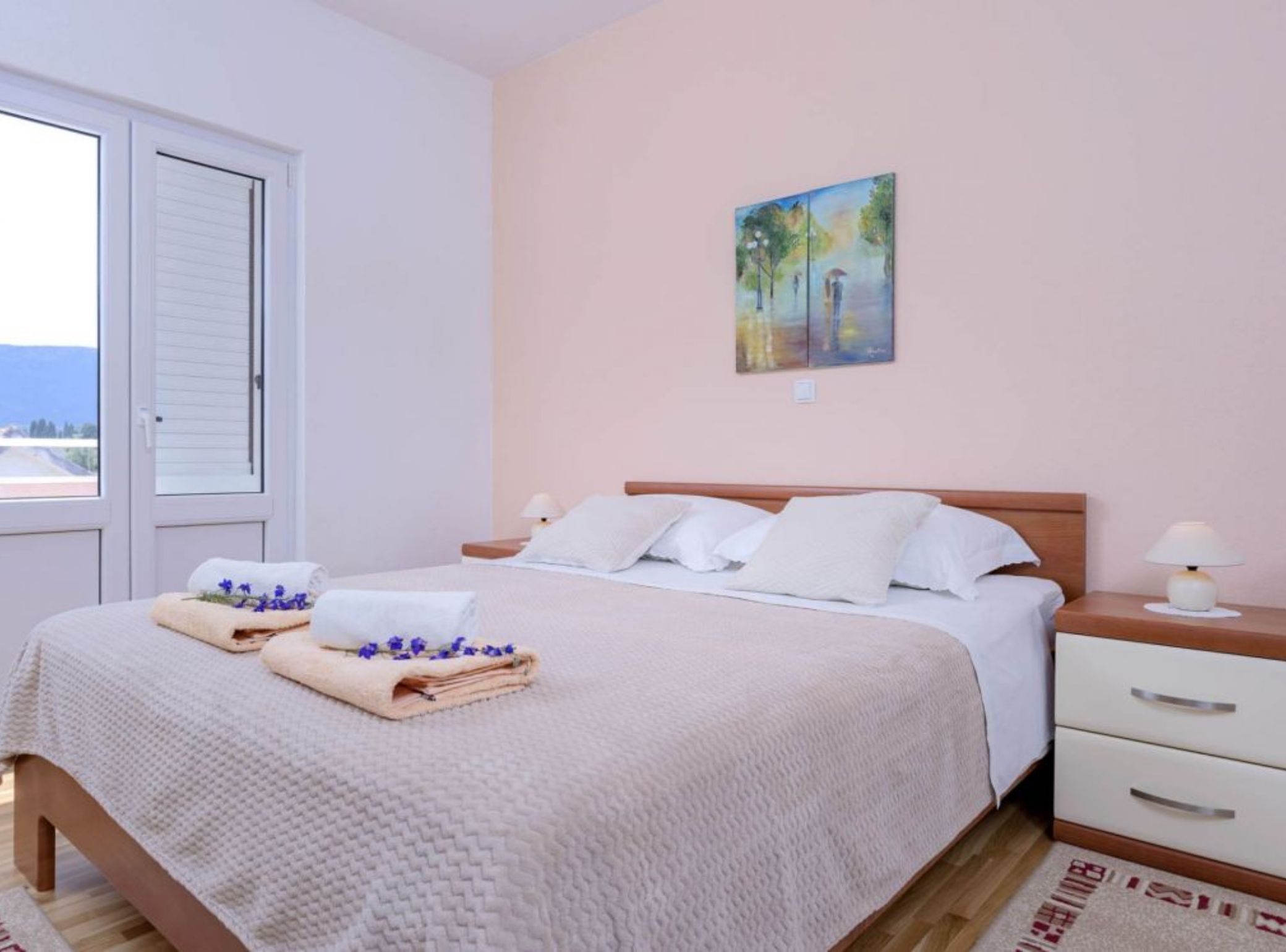 A neatly made bed with a white duvet, a wooden headboard, and a bedside table with a lamp.