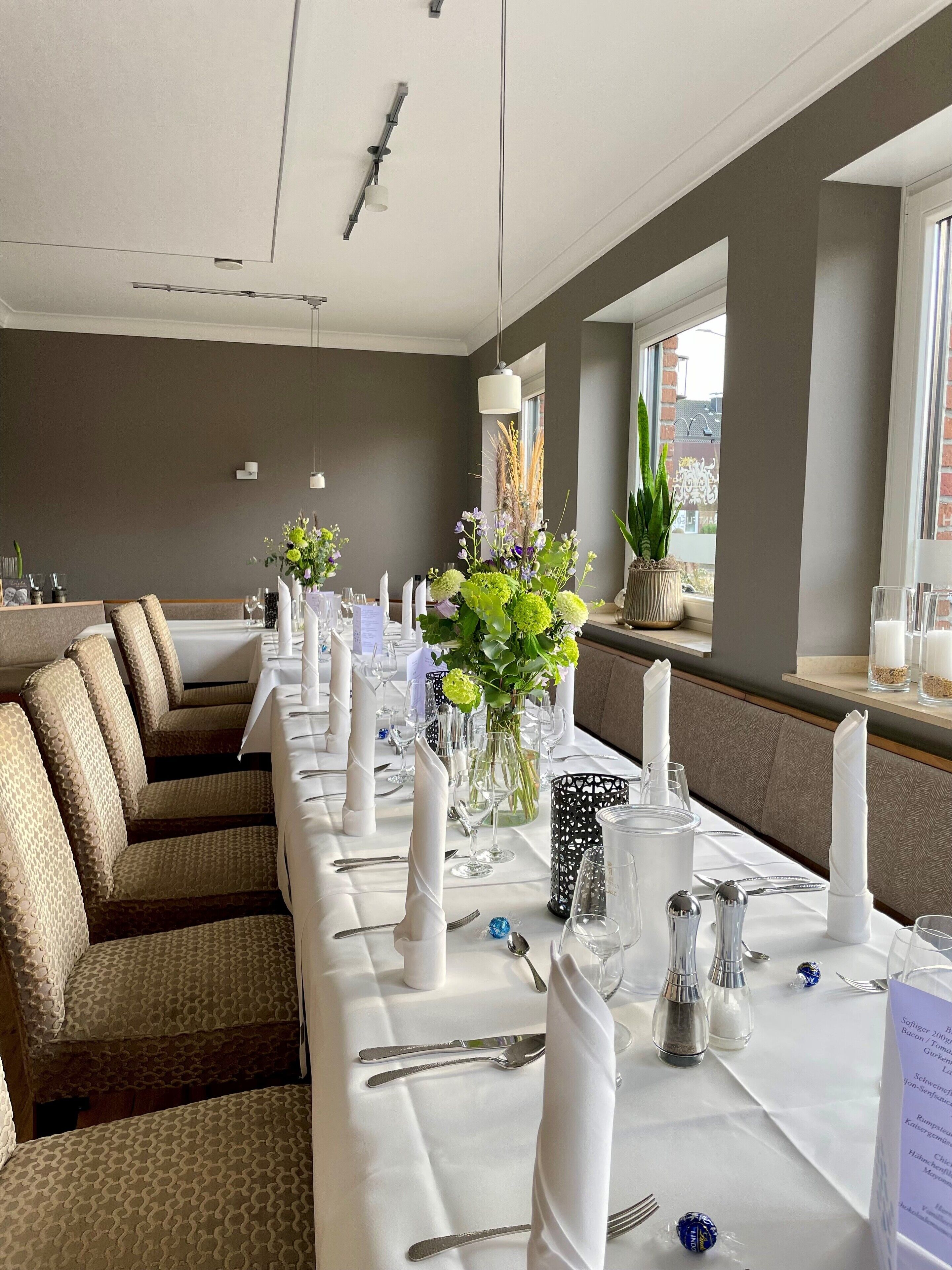 A long dining table set with white tablecloths, glassware, and neatly folded napkins.