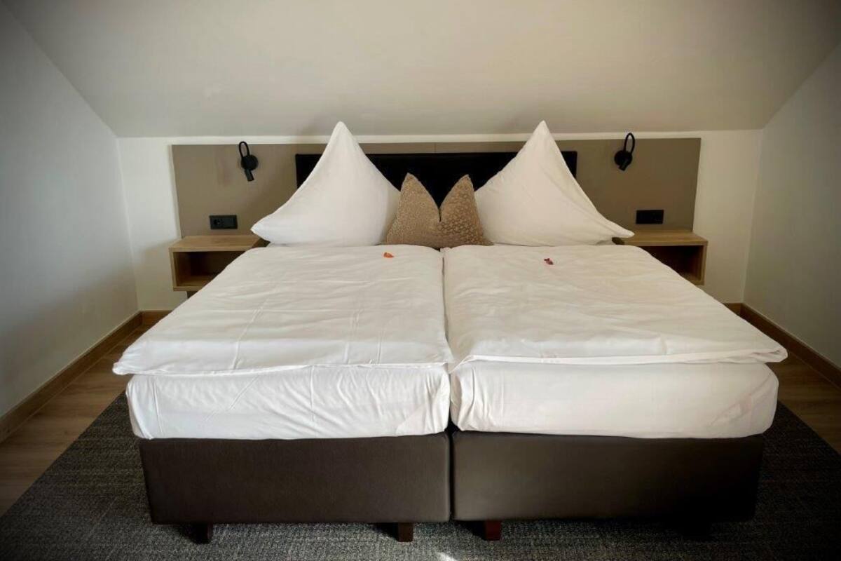 Una cama doble con ropa de cama blanca y dos mesitas de noche con lámparas.