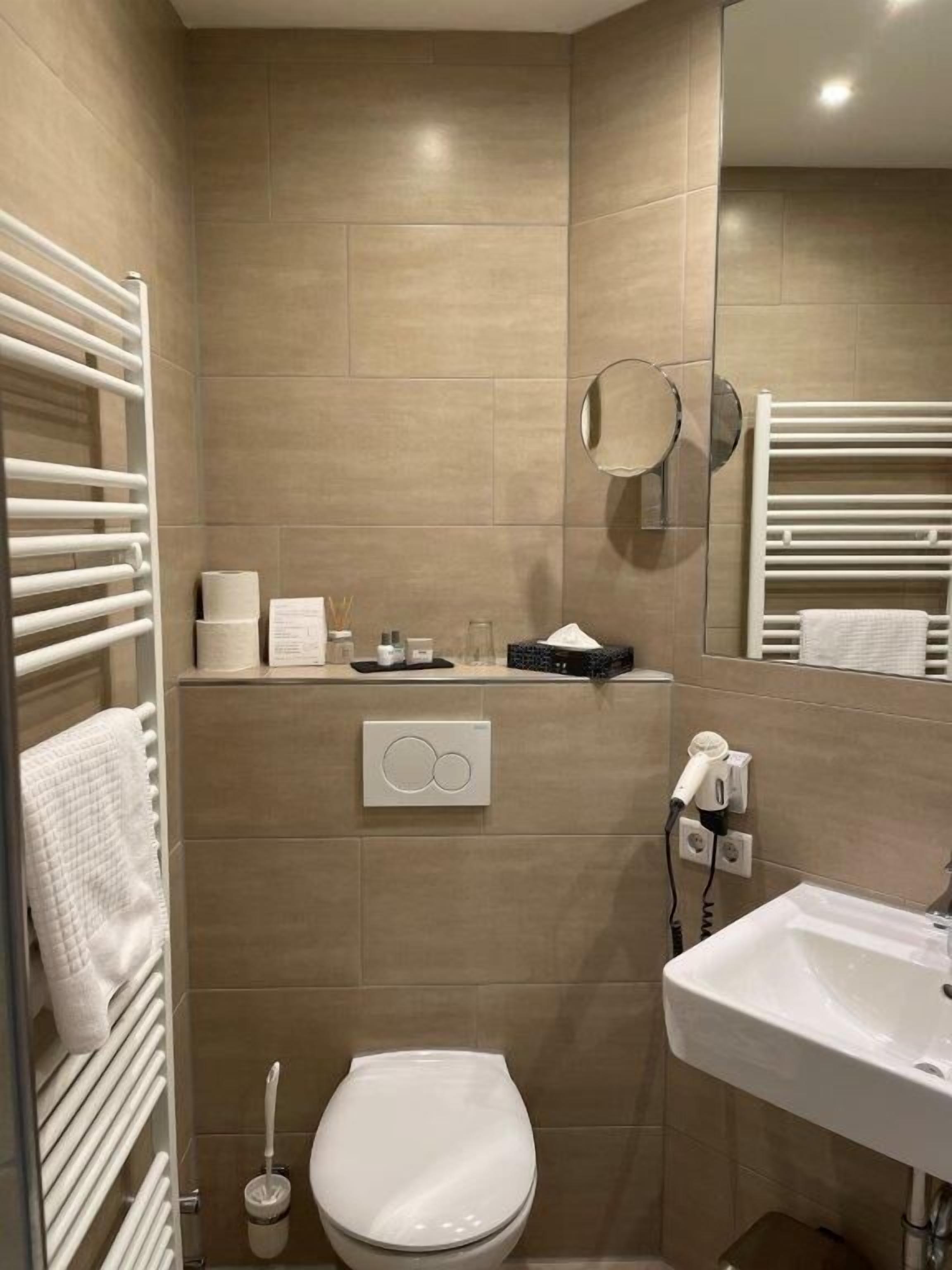 A modern bathroom with a toilet, sink, towel rack, and a mirror.