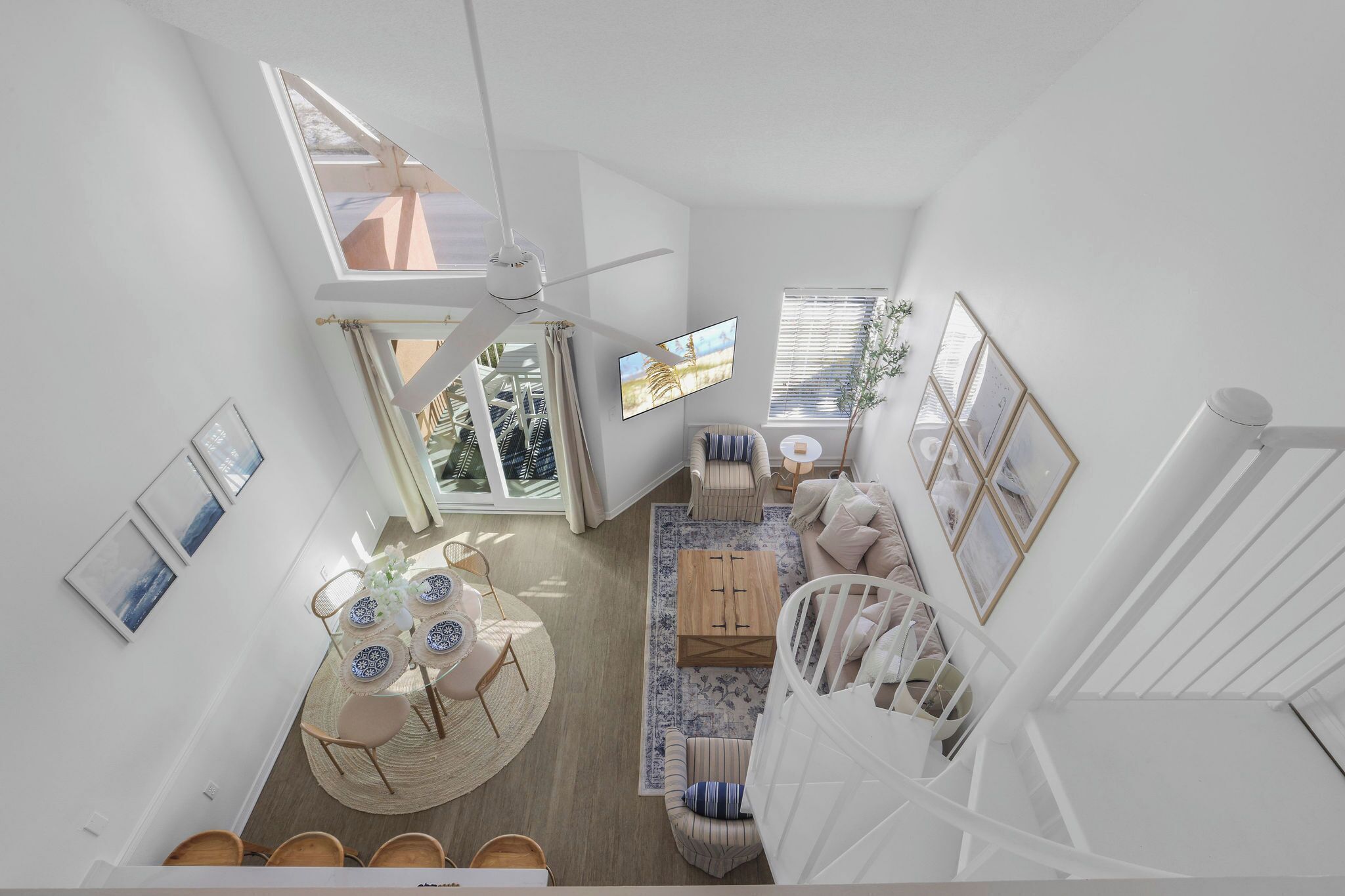 Una habitación amplia con zona de comedor, sofá, cuna y ventilador de techo.