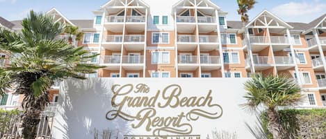 Ein mehrstöckiges Gebäude mit Balkonen und einem Schild, auf dem "The Grand Beach Resort Condominium" steht.