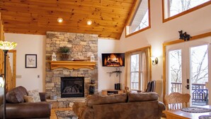 A cozy living room with a stone fireplace, leather sofas, and a wooden ceiling. - Wilderness Ridge - Starry Nights & Mountain Sights - Pet Friendly (Sevierville)